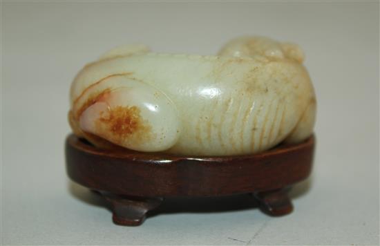 A Chinese pale celadon and russet jade recumbent figure of a bixi, 19th century, 5cm, wood stand